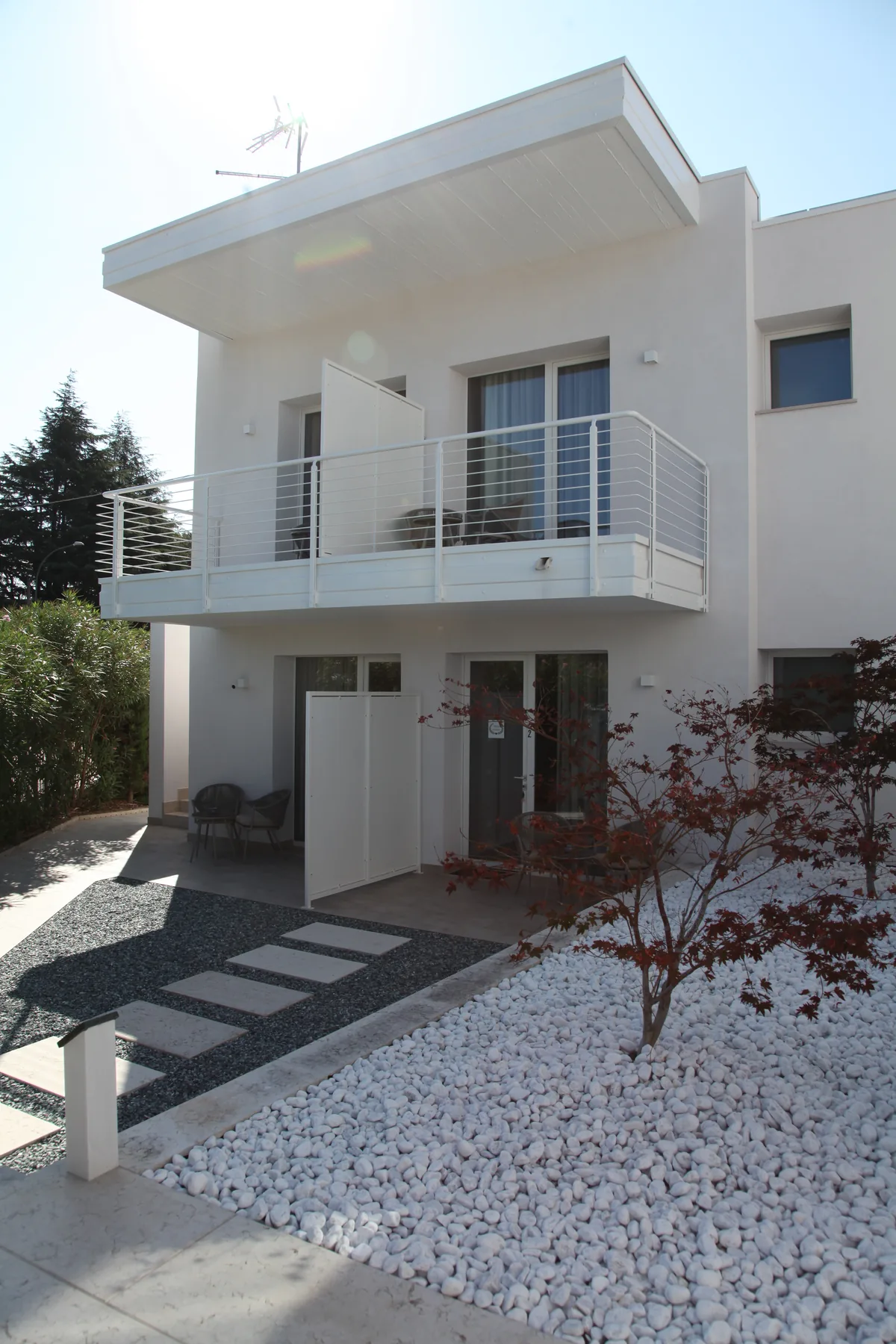 White exterior, balconies and garden entrances at Harmony Affi